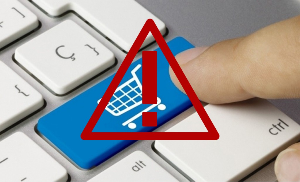 Dedo em cima de um teclado com botão azul com desenho de carrinho de compras e um triangulo com exclamação vermelho em cima.
