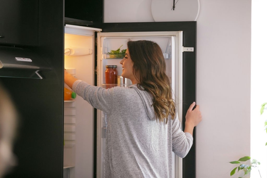 Uma mulher abrindo uma geladeira.